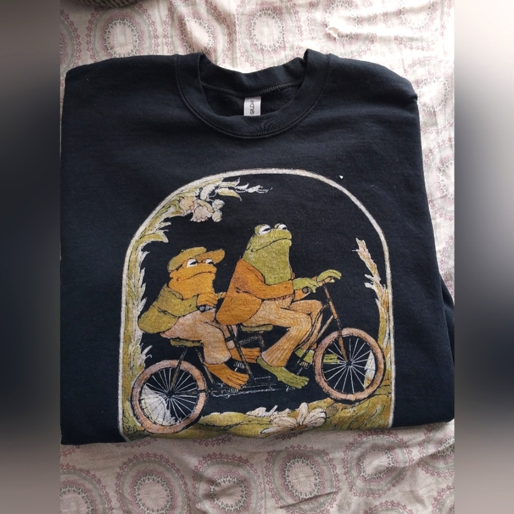 Large frog and toad on a bicycle, black long sleeve cuffed end sweater